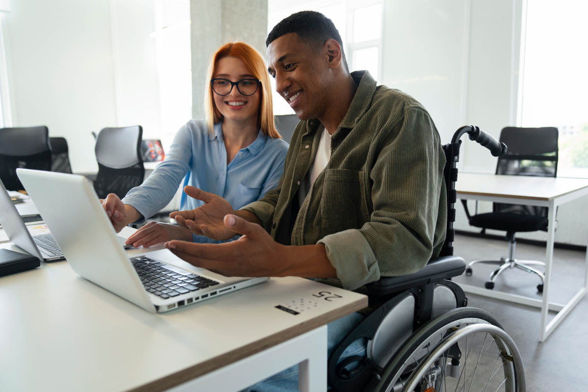 A man in a wheelchair discussing work with his female colleague