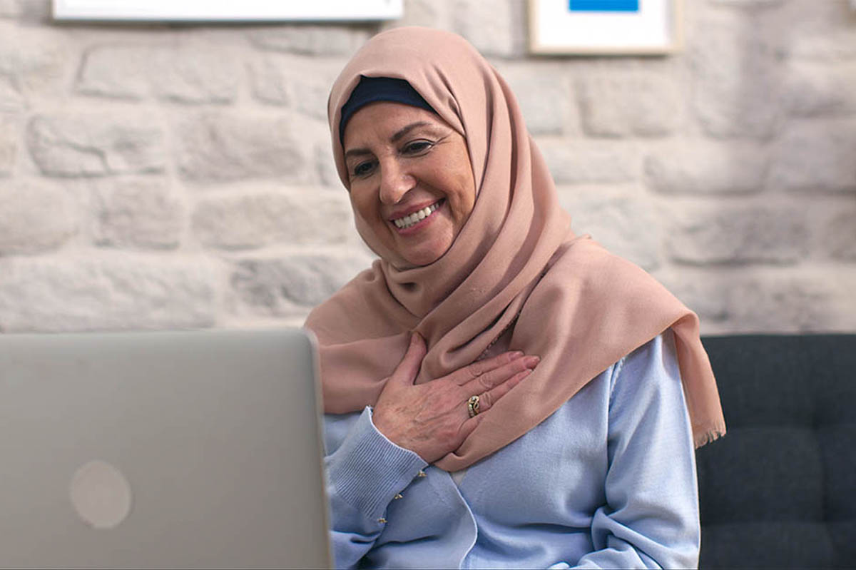 Elderly woman in a hijab makes a video call on the computer webcam.