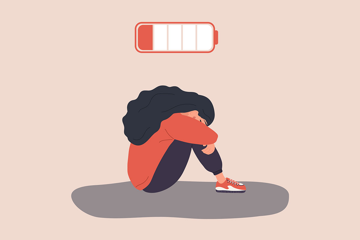 An illustration of a woman sitting on the floor with her head in her knees. A low battery icon hovers above her head.