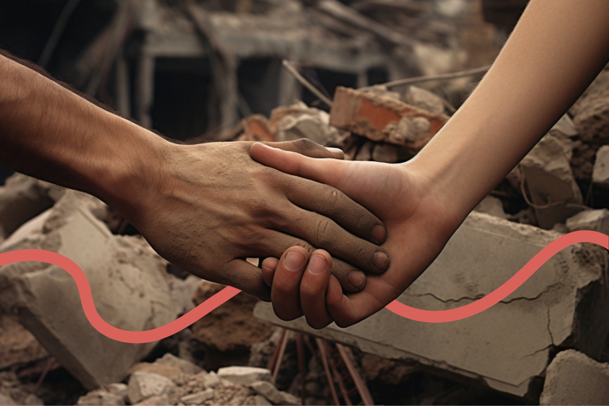 Image of two people holding hands close up with rubble and bricks in the background